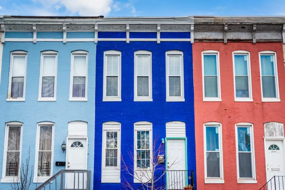 Brightly colored pale blue, dark blue, and coral row houses in Baltimore, Maryland.